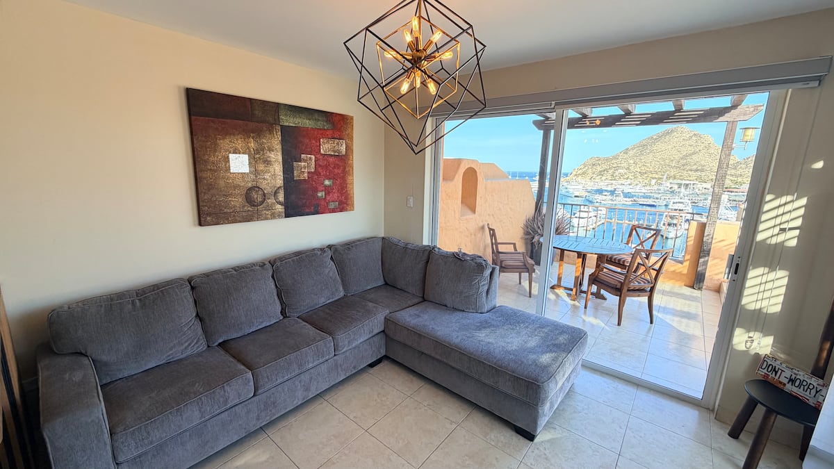 Living room opening onto the sunlit terrace and the marina beyond